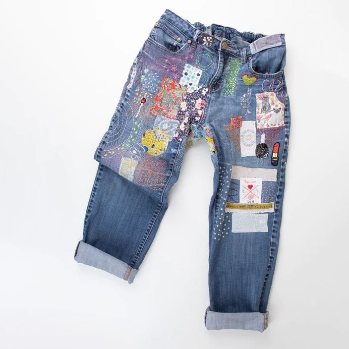 a mended pair of denim jeans with patches and stitching