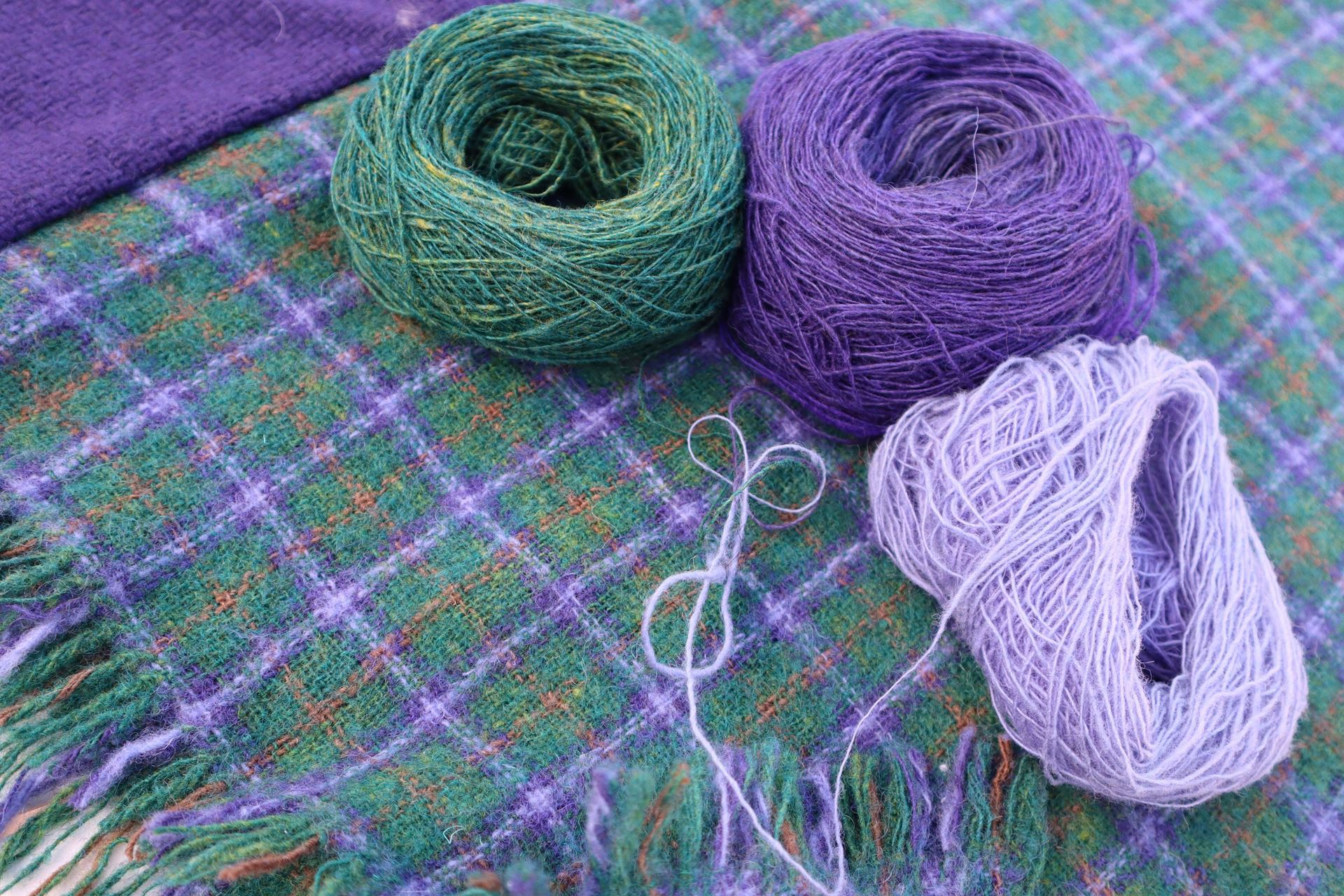 a woven fabric with three balls of handspun yarn on top